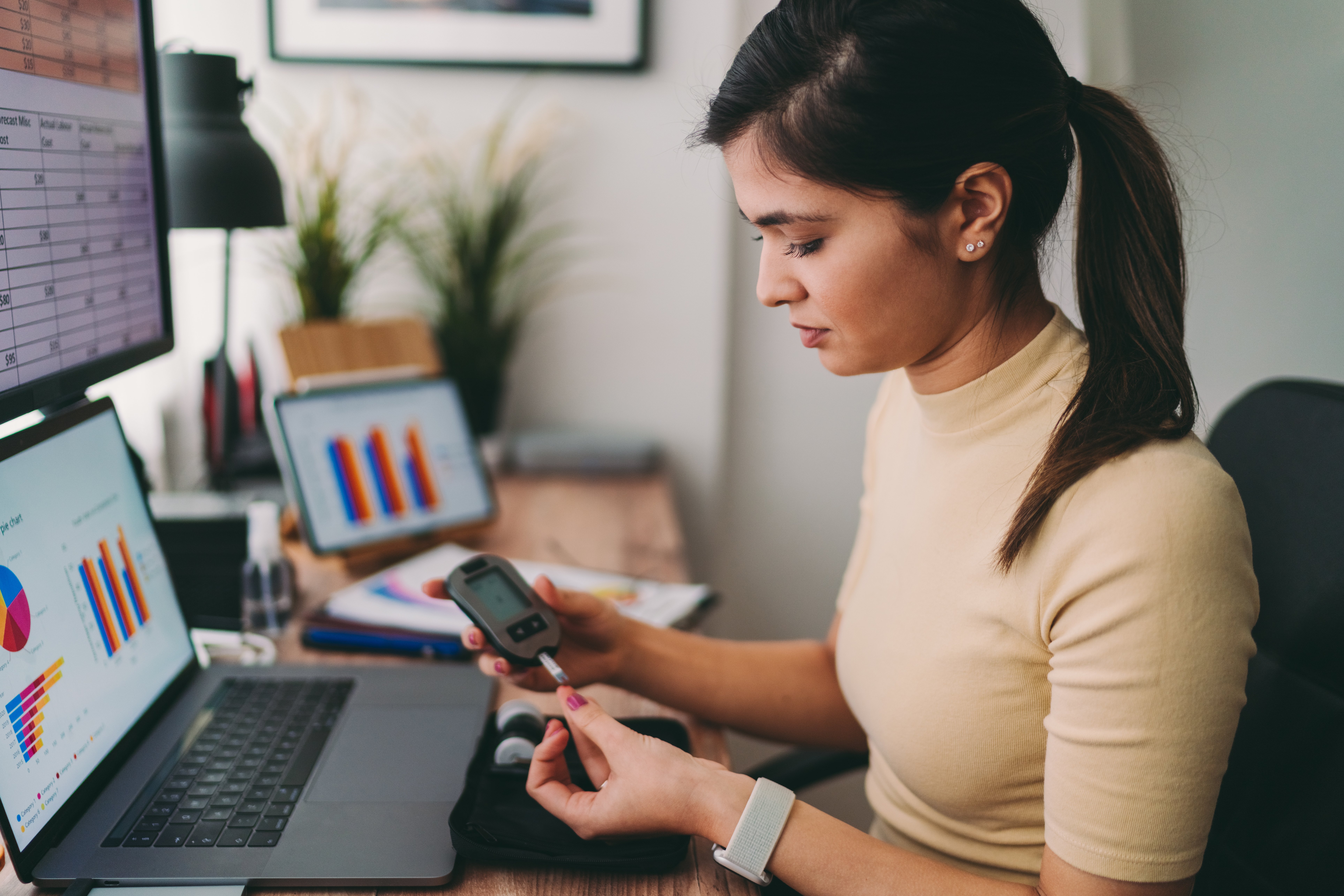 Woman with computer graphs in front of her checking glucose